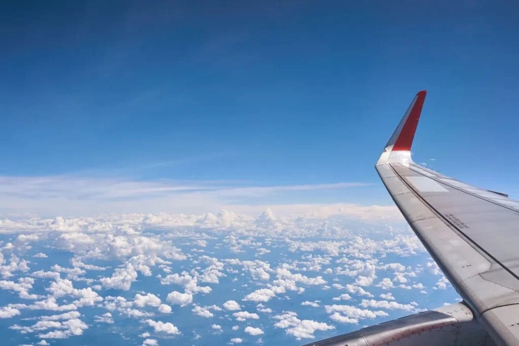 View of the wing of an aircraft flying above the clouds.