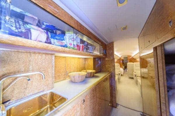 The aircraft interior features a galley with a sink and snack storage.