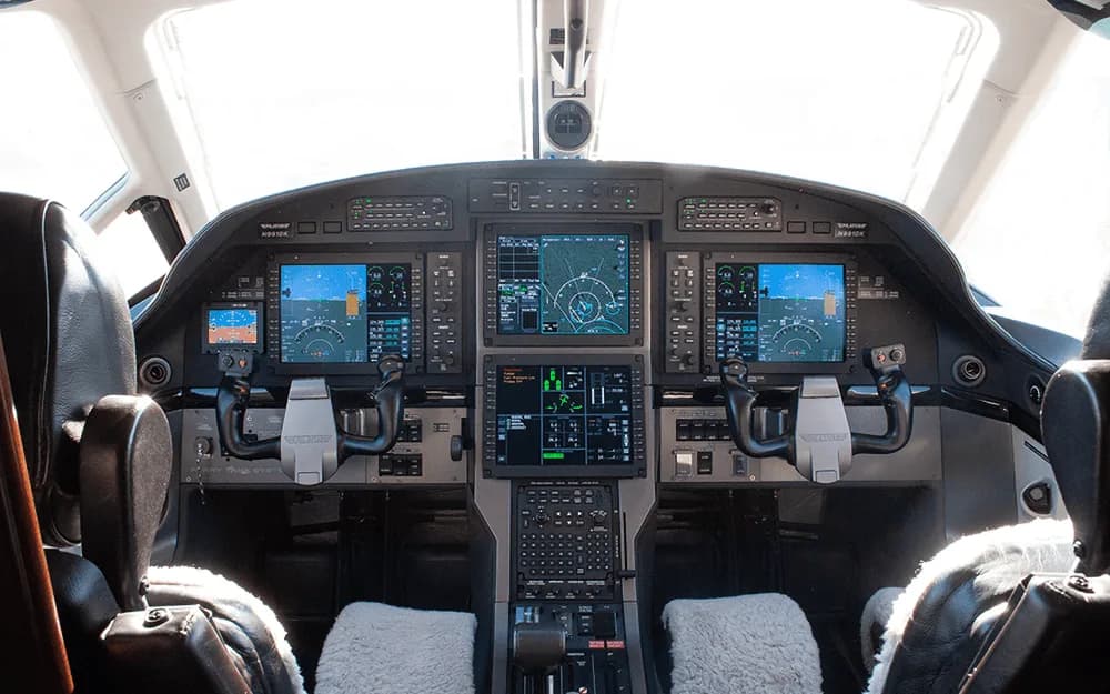 The modern glass cockpit of a Pilatus PC-12 aircraft with multiple digital displays and controls.