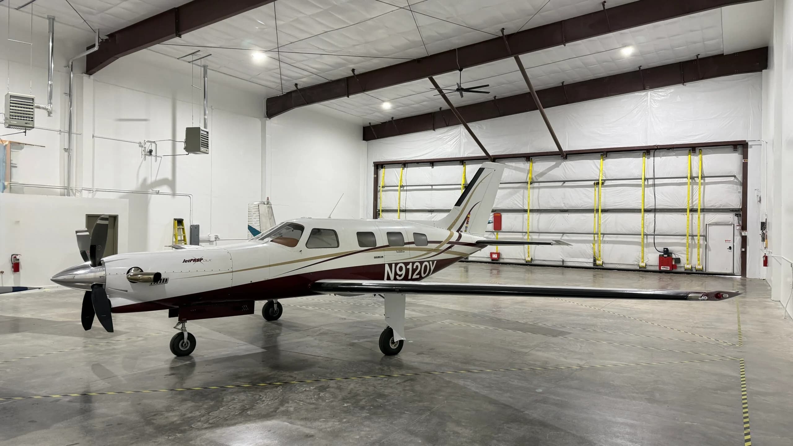 A Piper aircraft is parked inside a hangar.