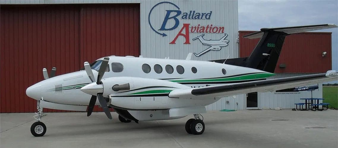 King Air 85SD parked in front of a hangar with Ballard Aviation logo.