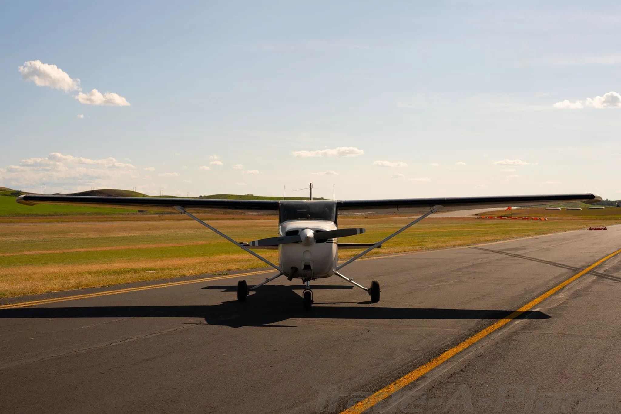 A head-on view of a white Cessna 172 with black stripes, tail number N738ZT, on an airfield.