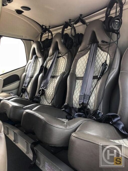 Interior view of the helicopter cabin with leather seats and headsets.