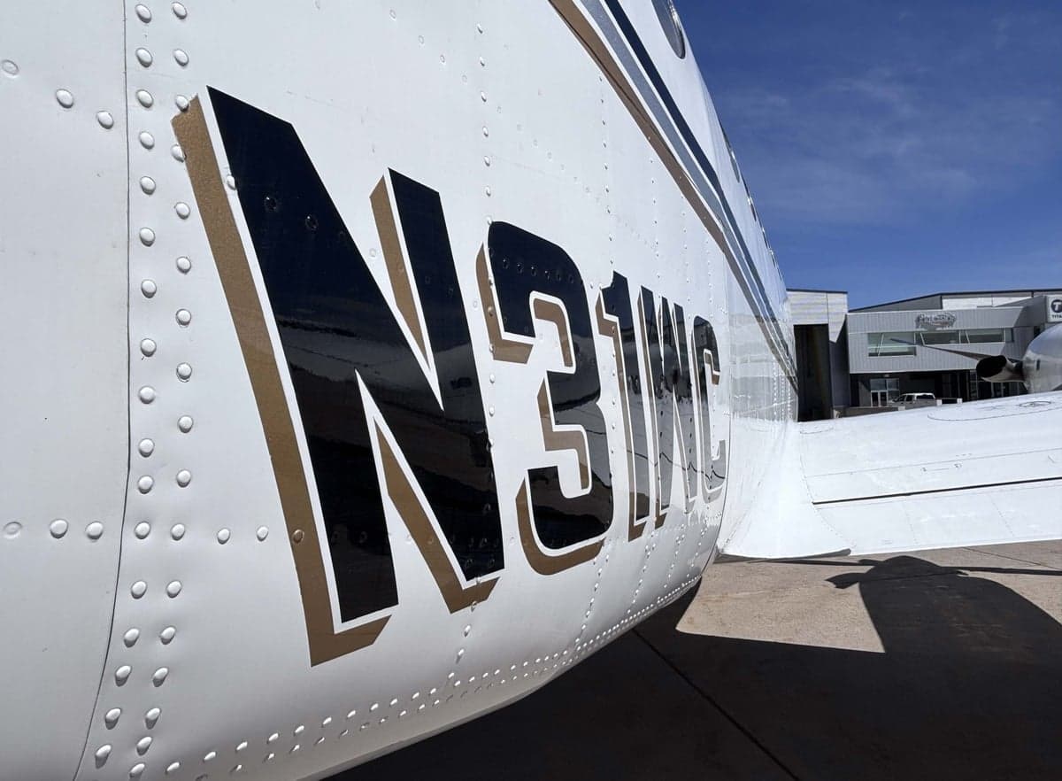 Close-up view of the N31WC tail number on the white fuselage with black and gold stripes.