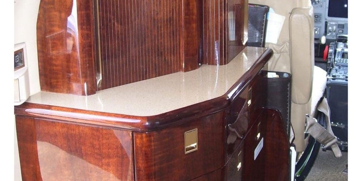 A detailed view of the polished wooden cabinetry and countertop inside the cabin of a private jet.