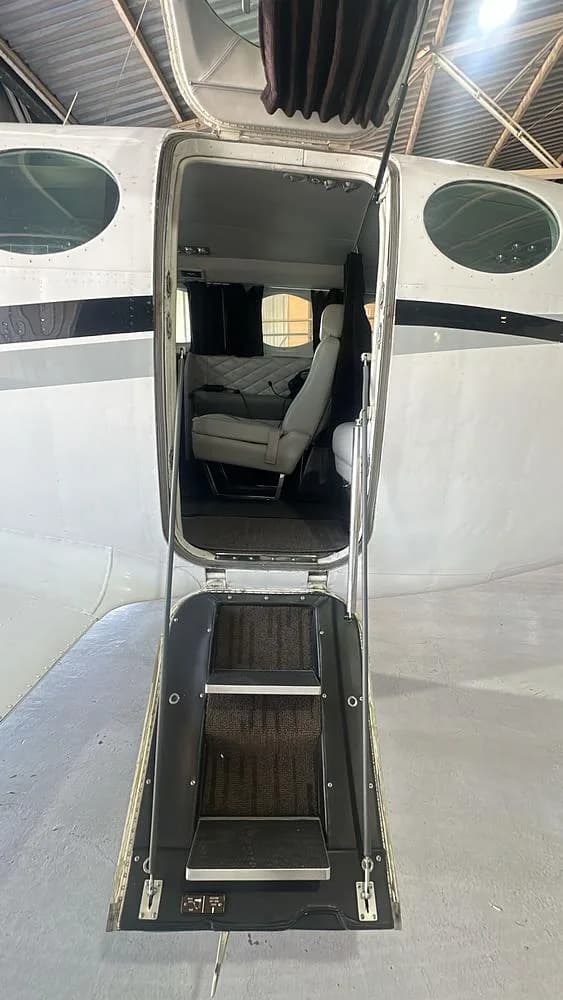 The open airstair door of a Cessna 421 aircraft, showing the steps and a view into the cabin with grey seats.
