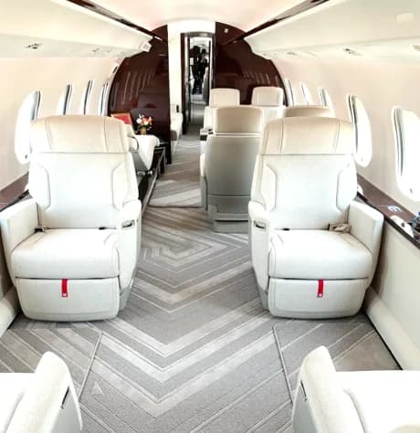 View of the aircraft interior with white leather seats and patterned carpet.