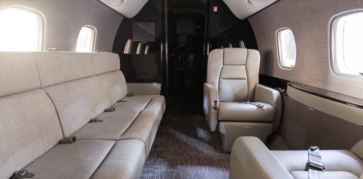 View of the aircraft cabin with a gray sofa and leather seats.
