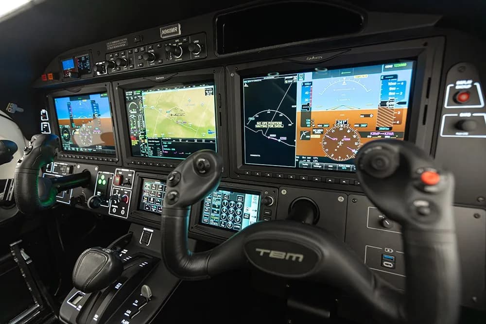 A close-up view of the TBM 960 cockpit instrument panel with Garmin displays and controls.