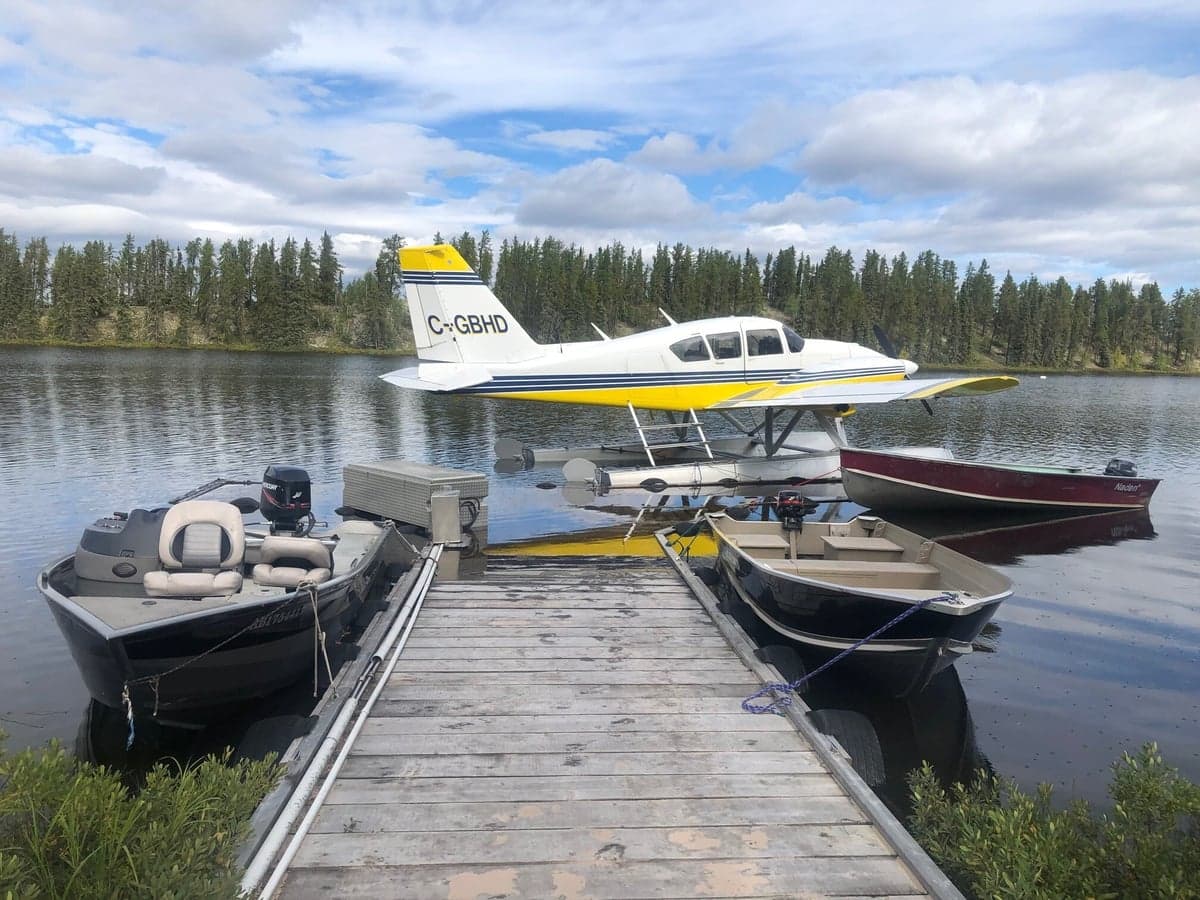 Front side view of the yellow and white twin engine aircraft on floats, inside a hangar.