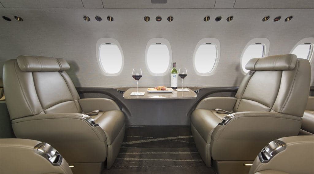 A view of the Citation Latitude cabin with leather seats and a table set for wine and snacks.