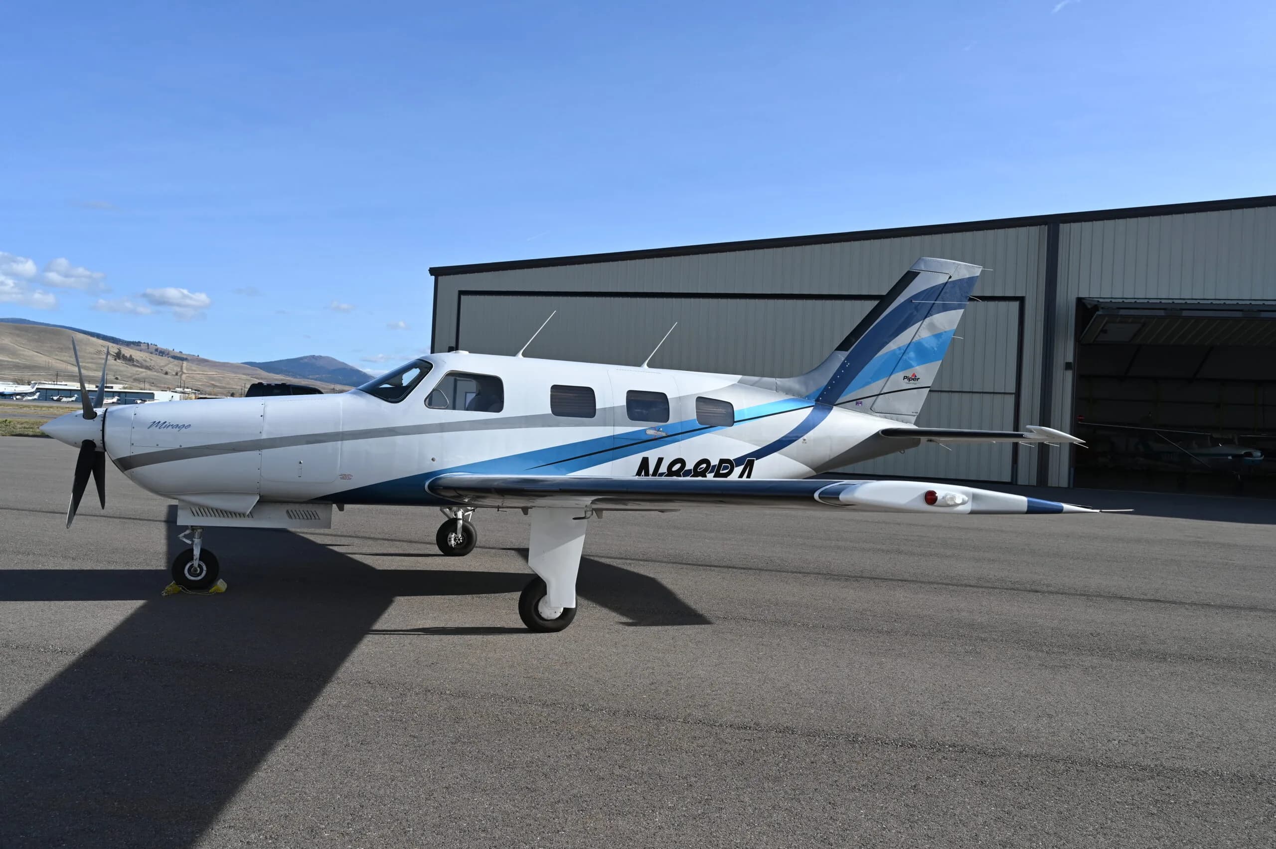 Piper Mirage N10QD1 parked on the tarmac in front of a hangar.