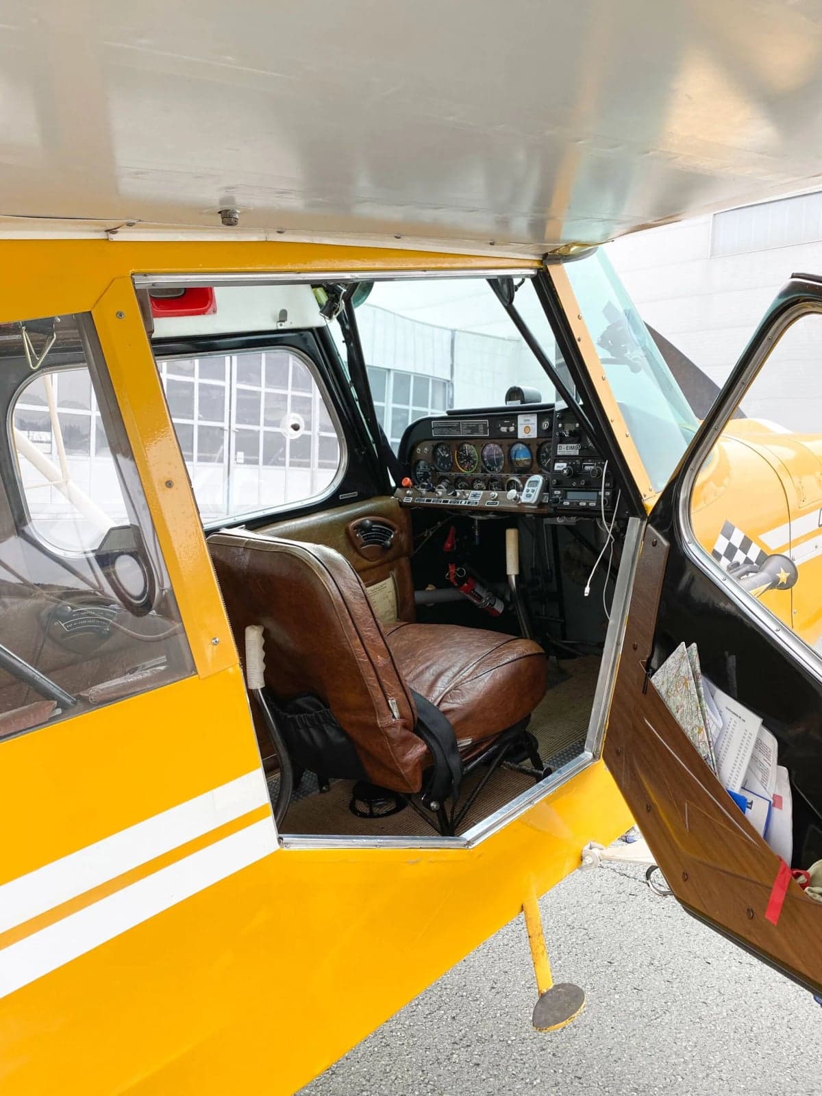 Side view of a yellow and white aircraft, D-EIMU, parked on the tarmac in front of a building.