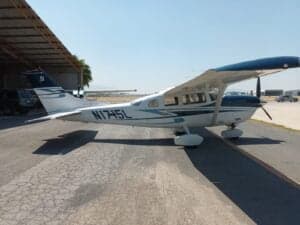 A Cessna aircraft with blue and white paint scheme, parked on the tarmac with the tail number N1715L visible.