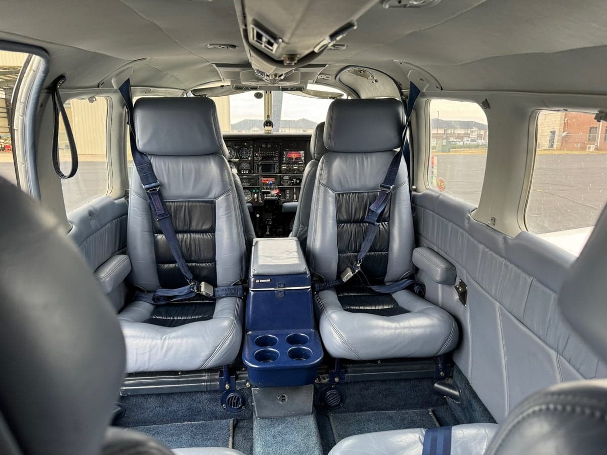 View from the rear of the aircraft cabin looking forward at the blue front seats and cockpit.
