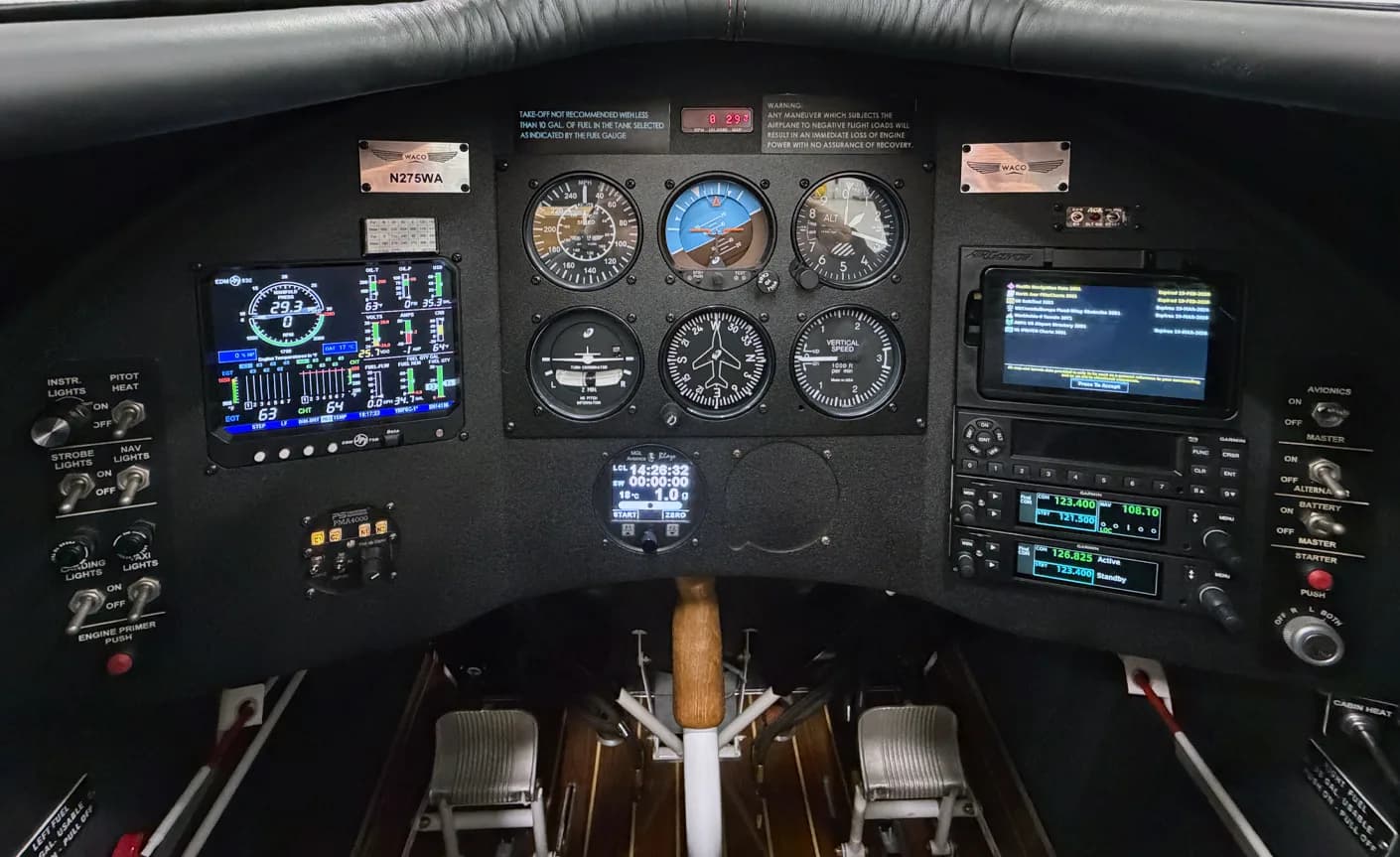 The instrument panel and seats of the biplane's cockpit are visible.