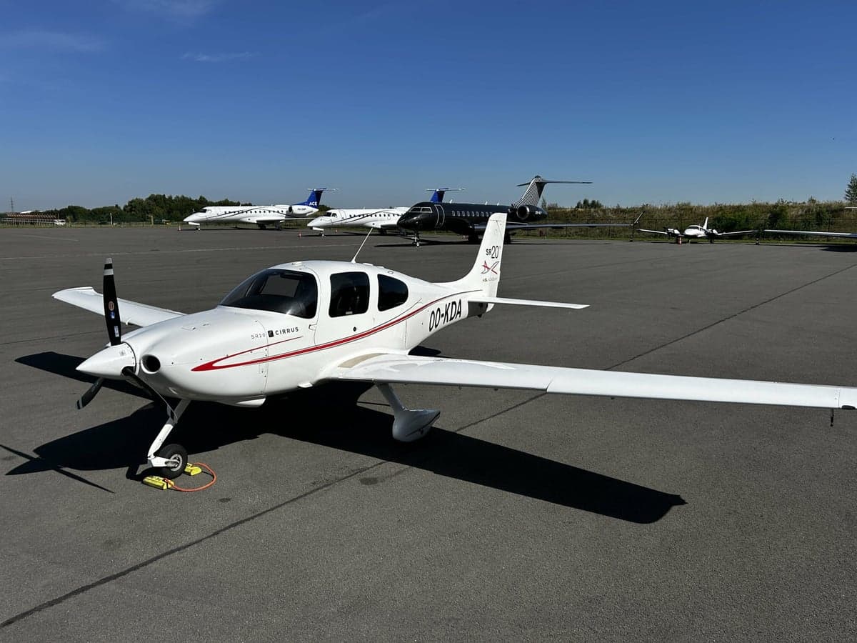 A Cirrus SR20 aircraft with registration OO-KDA parked on the tarmac.