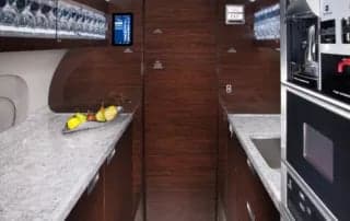 A galley area with a sink, microwave, oven, and fruit bowl.