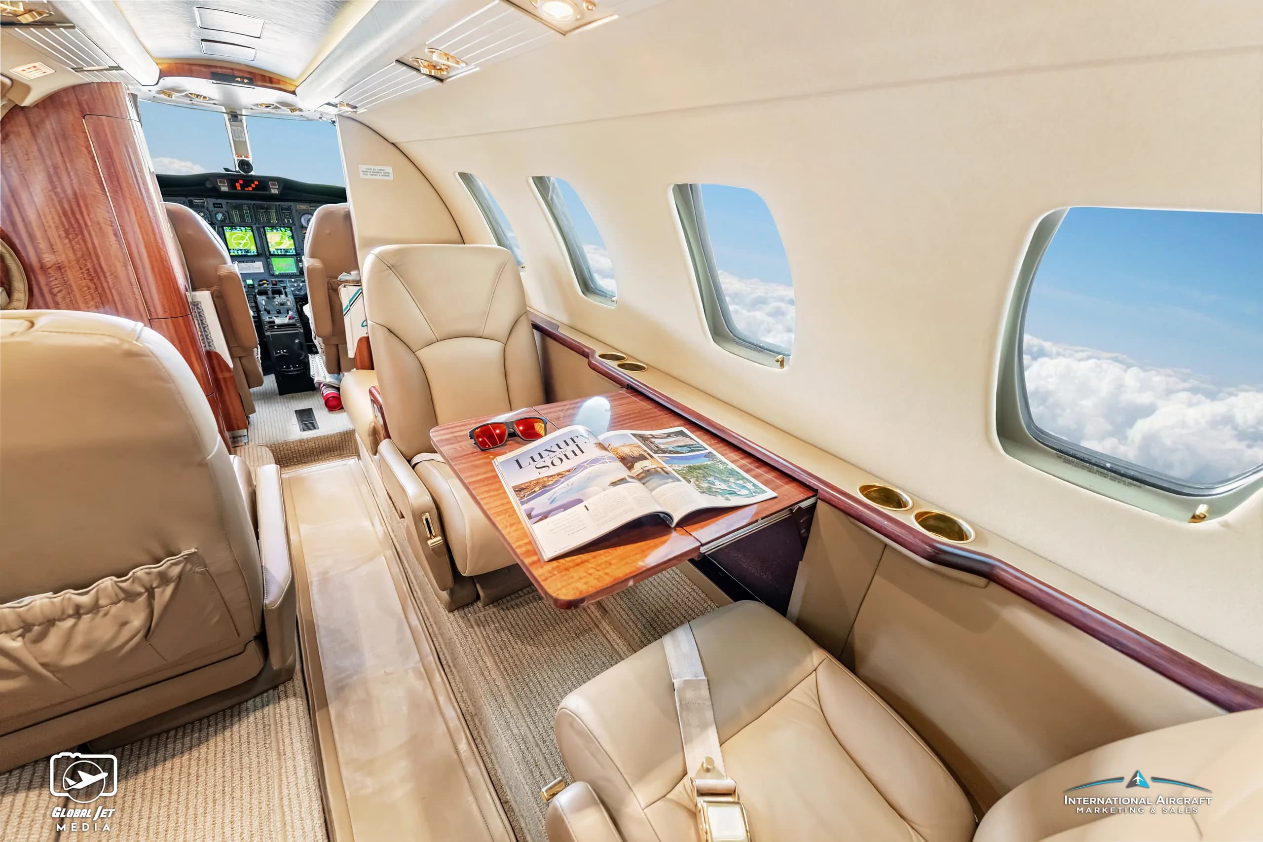 Interior of a Cessna Citation CJ1 with tan leather seats and a wood table.