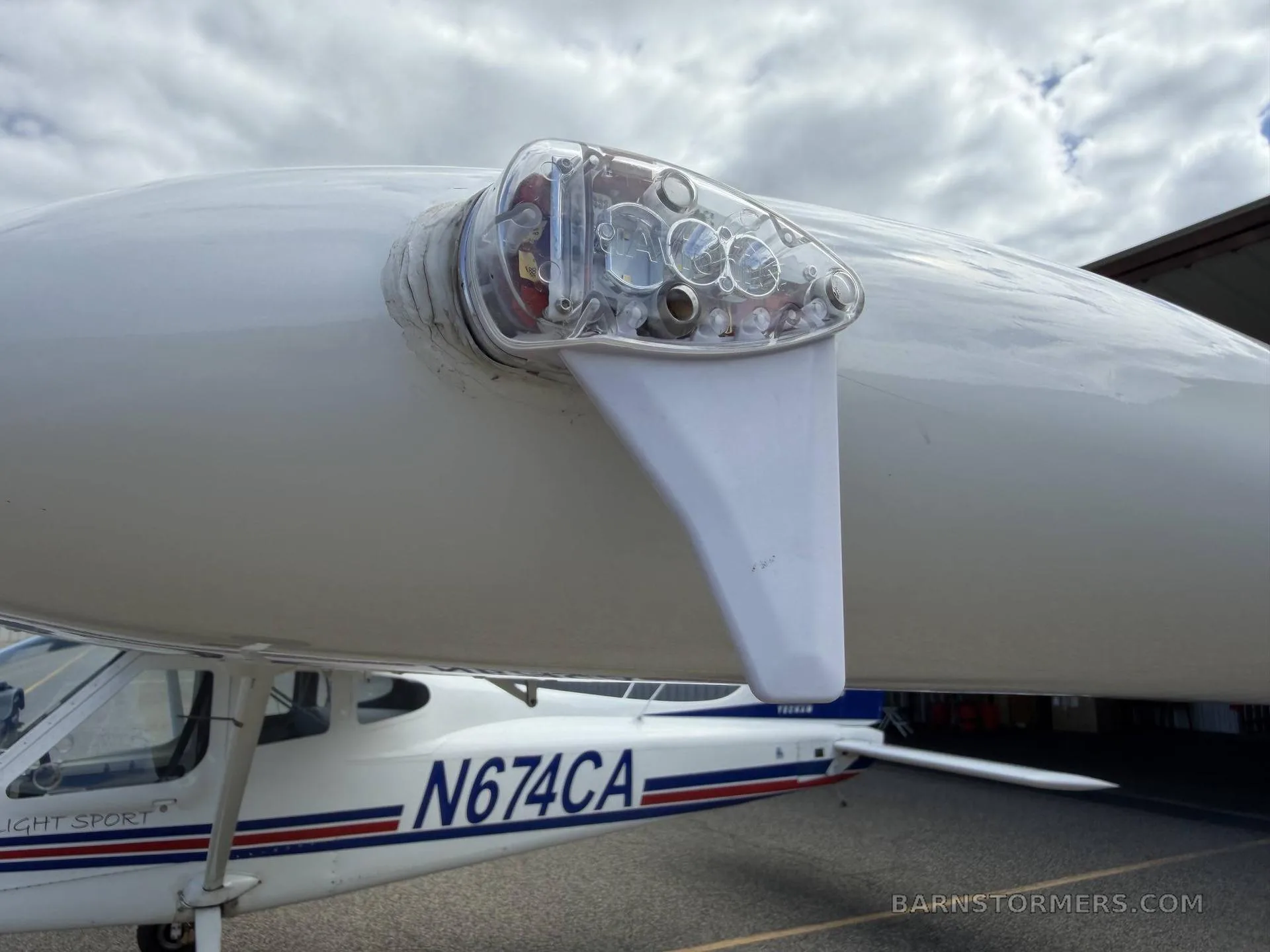 A close-up view of the clear wingtip navigation light on a white light sport aircraft.