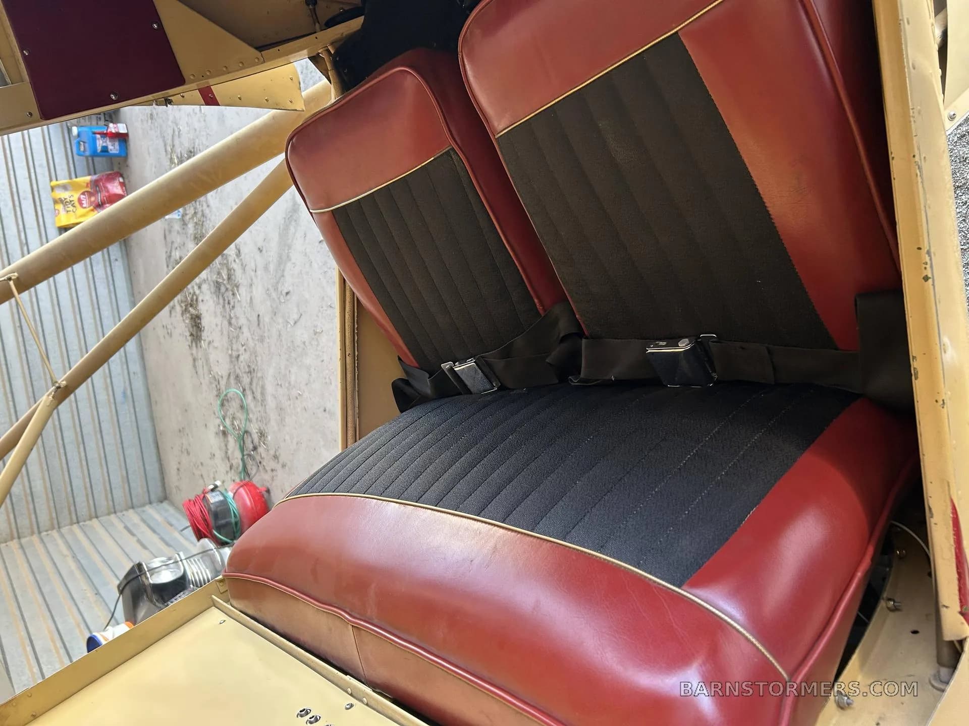 Close-up view of the red and black upholstered seats inside a vintage aircraft cabin.