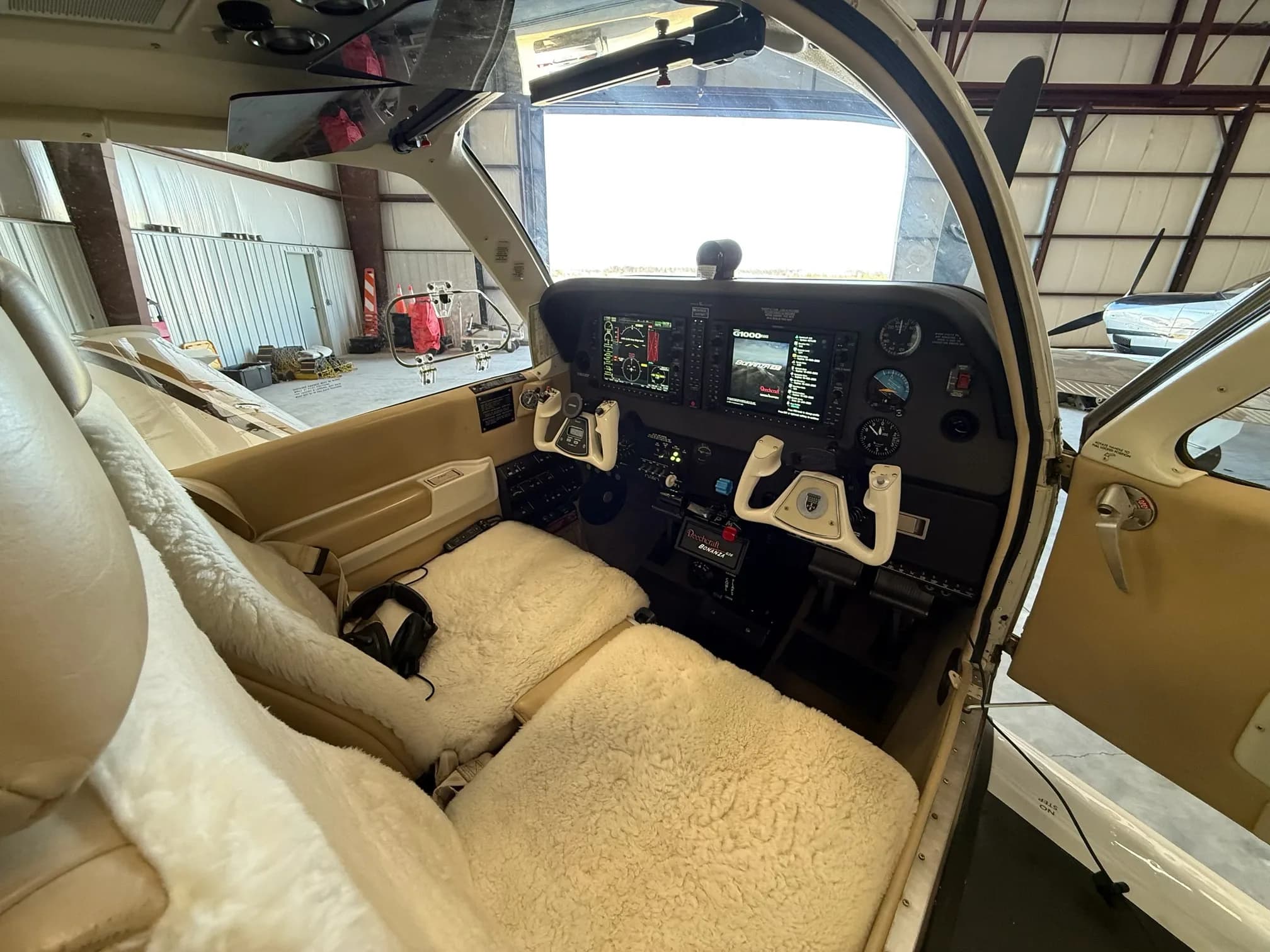 A wide view of the Beechcraft Bonanza cockpit with sheepskin seat covers and a modern instrument panel.