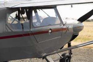Close up of the cockpit and propeller of a gray and red Cubcrafters XCub.