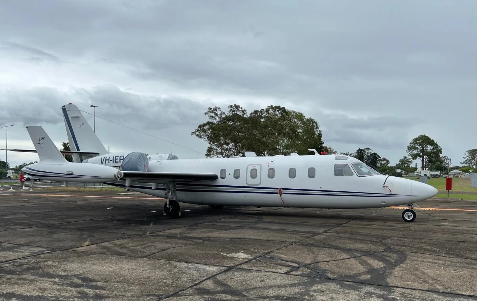 Side view of the VH-IER aircraft on the tarmac under a cloudy sky.