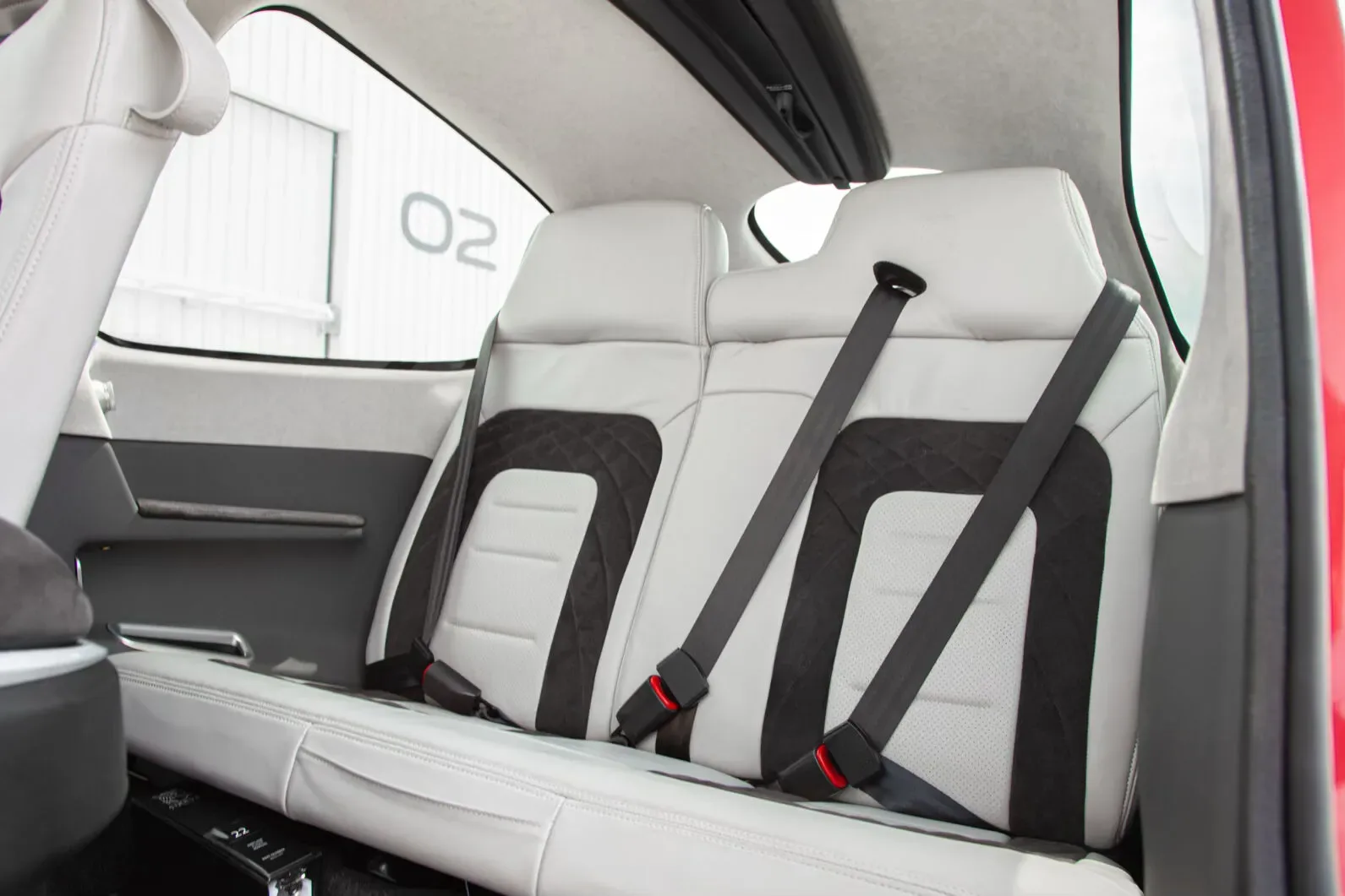 The white and black rear passenger seats of the aircraft cabin, with seatbelts visible.