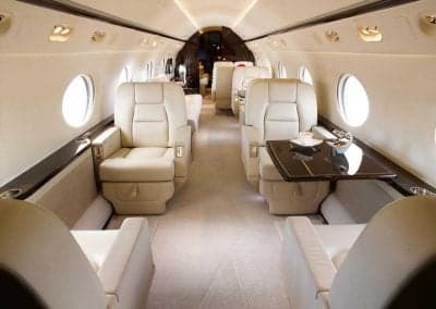 Aircraft interior featuring cream-colored seats and a table.