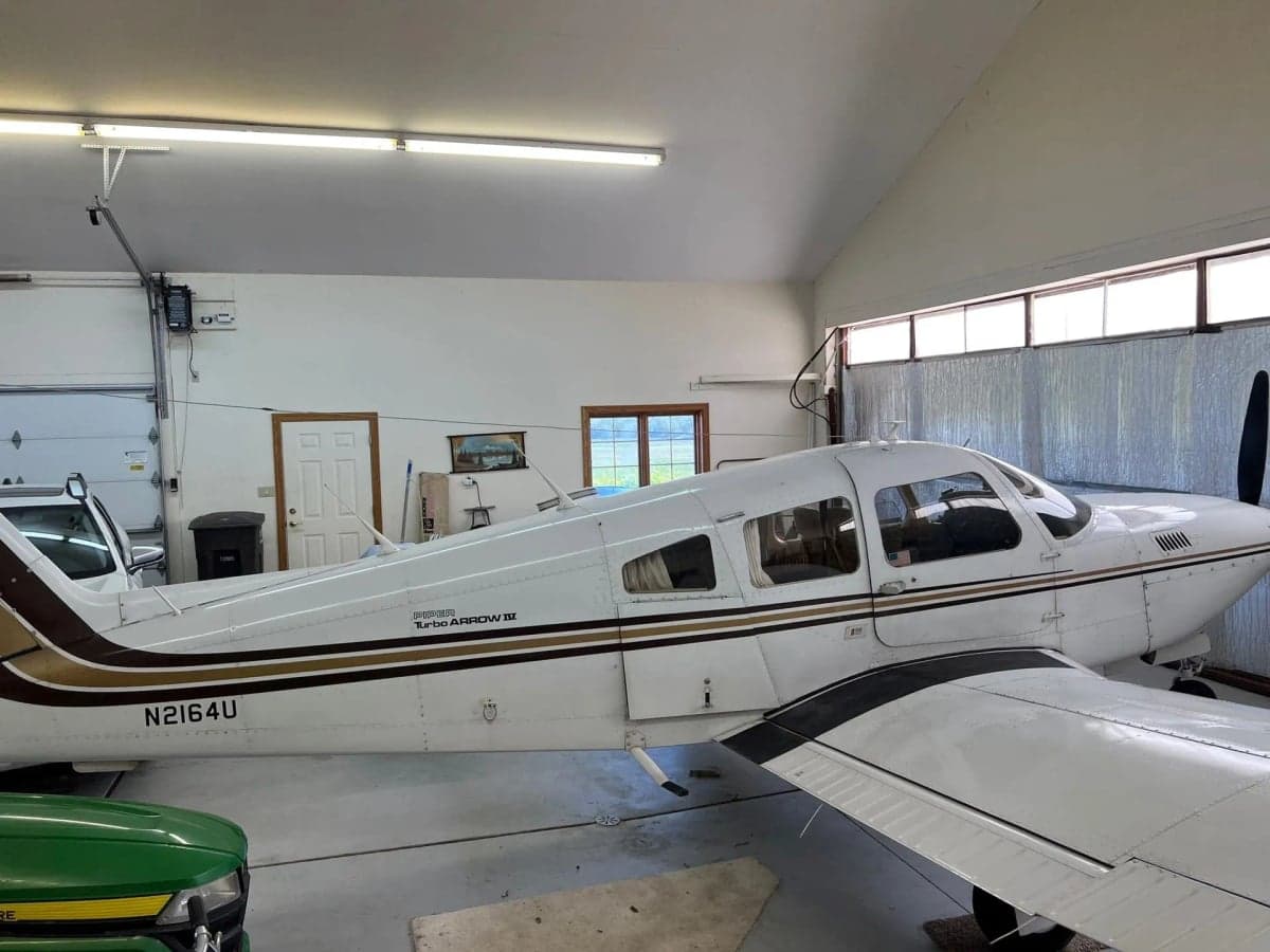 A Piper Turbo Arrow III aircraft with tail number N2164U parked inside a hangar.