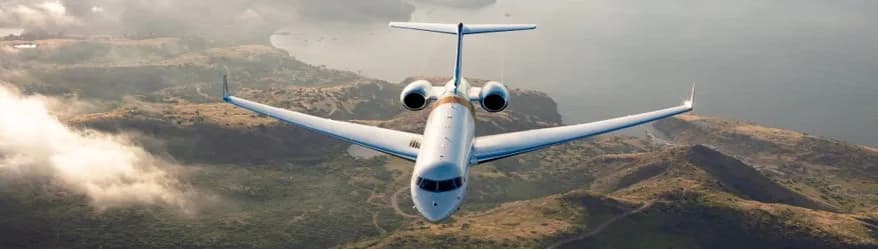 A private jet flies over a mountainous landscape.