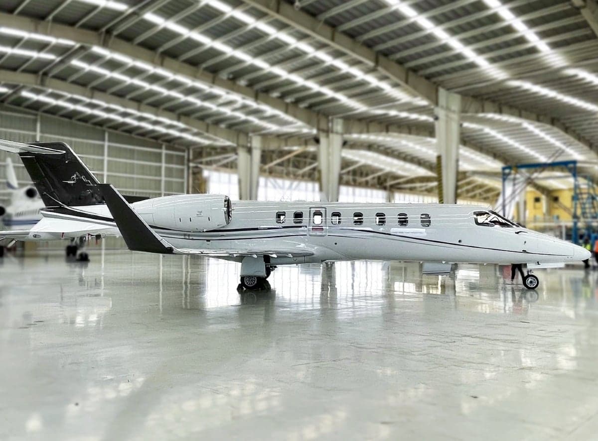 Side view of a light gray jet aircraft parked inside a hangar.