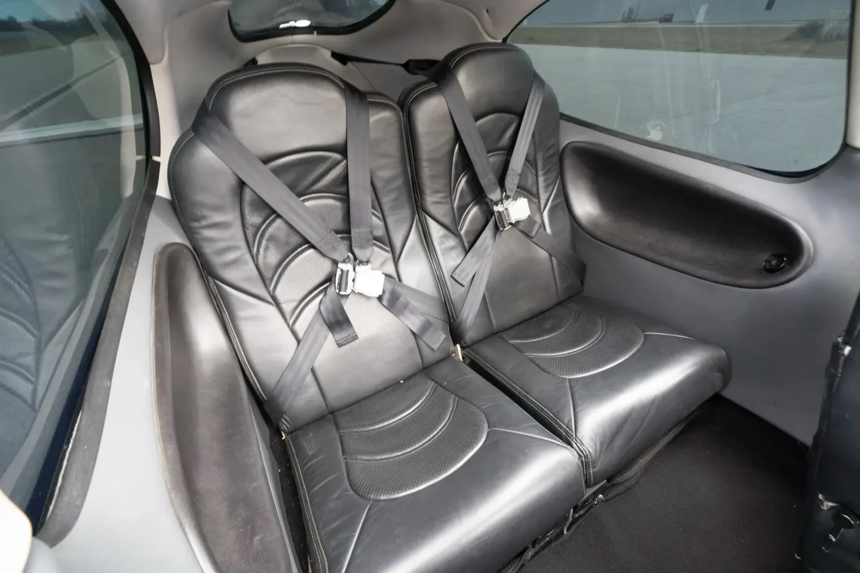 The black leather rear cabin seats with seatbelts in the Cirrus SR22 G3 Turbo aircraft, viewed from the side.