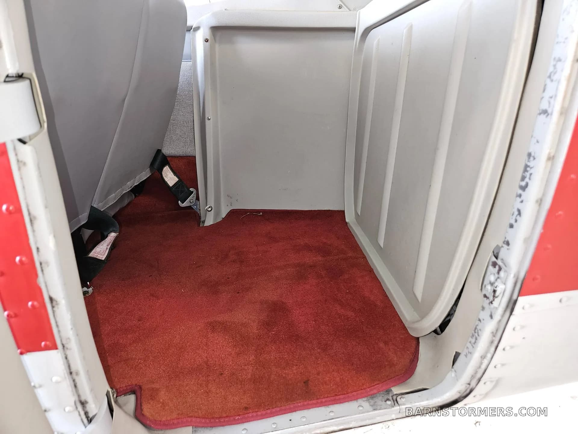 The red carpeted floor and rear seats of a small aircraft cabin.