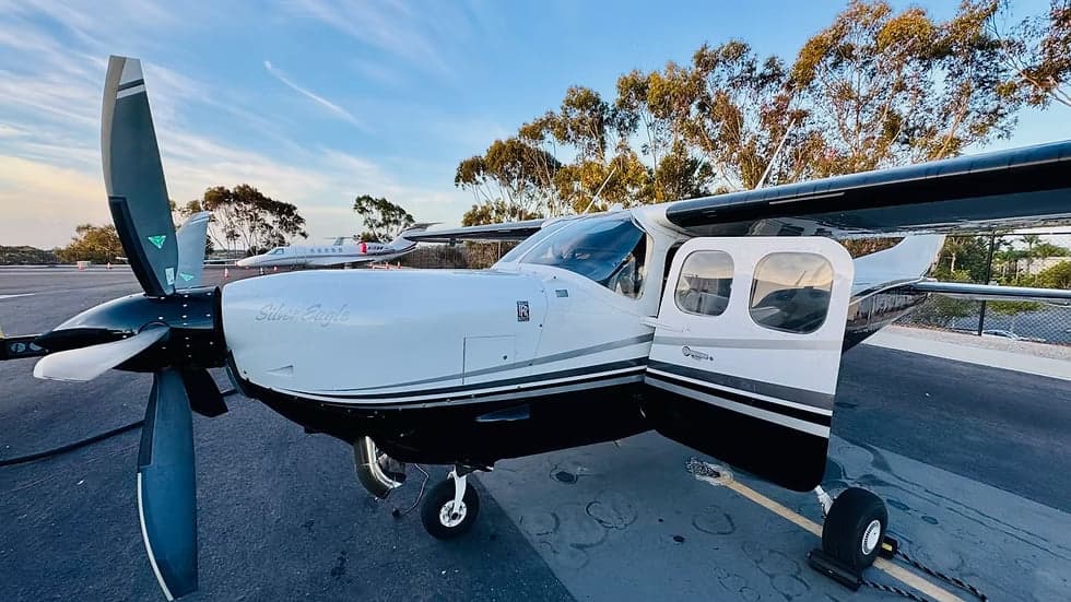A black and white Cessna 208B Grand Caravan, registration N22VF, is parked on the tarmac with its door open.