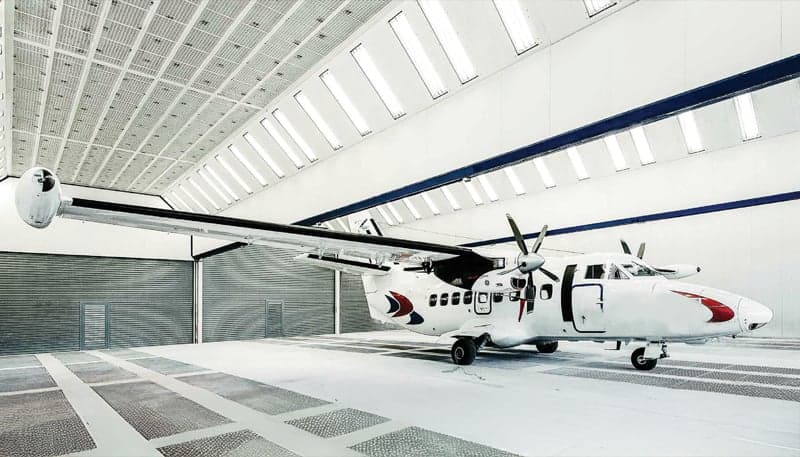Side view of a white and red de Havilland Canada DHC-6 Twin Otter inside a hangar.