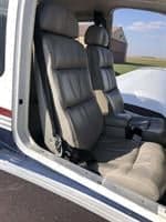 The interior of the aircraft features gray leather seats with seatbelts.