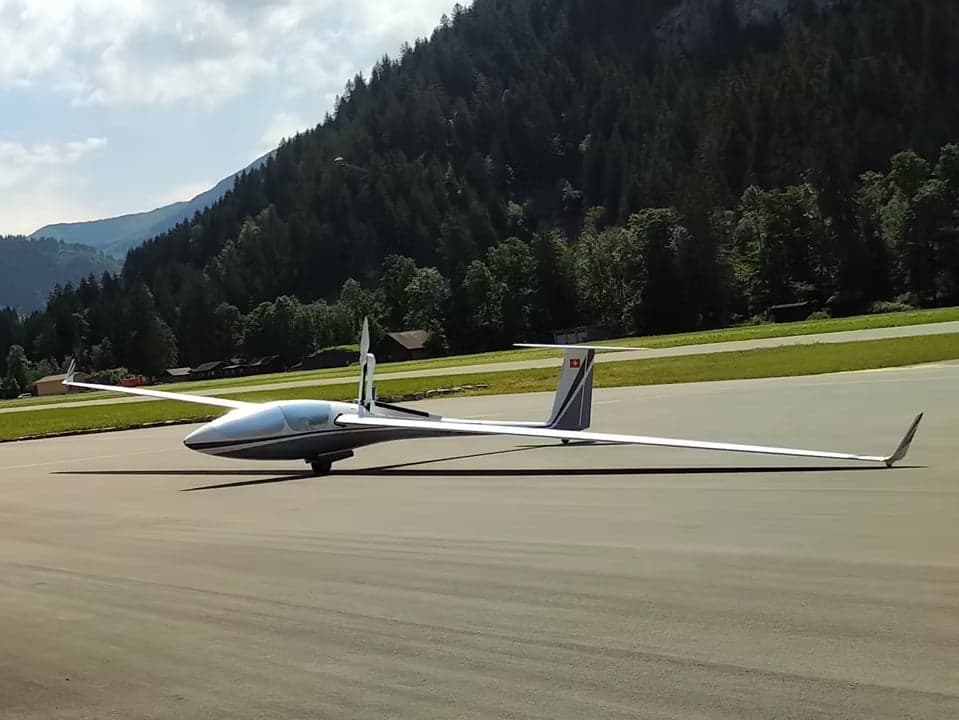 A glider with open cockpit on the ground.