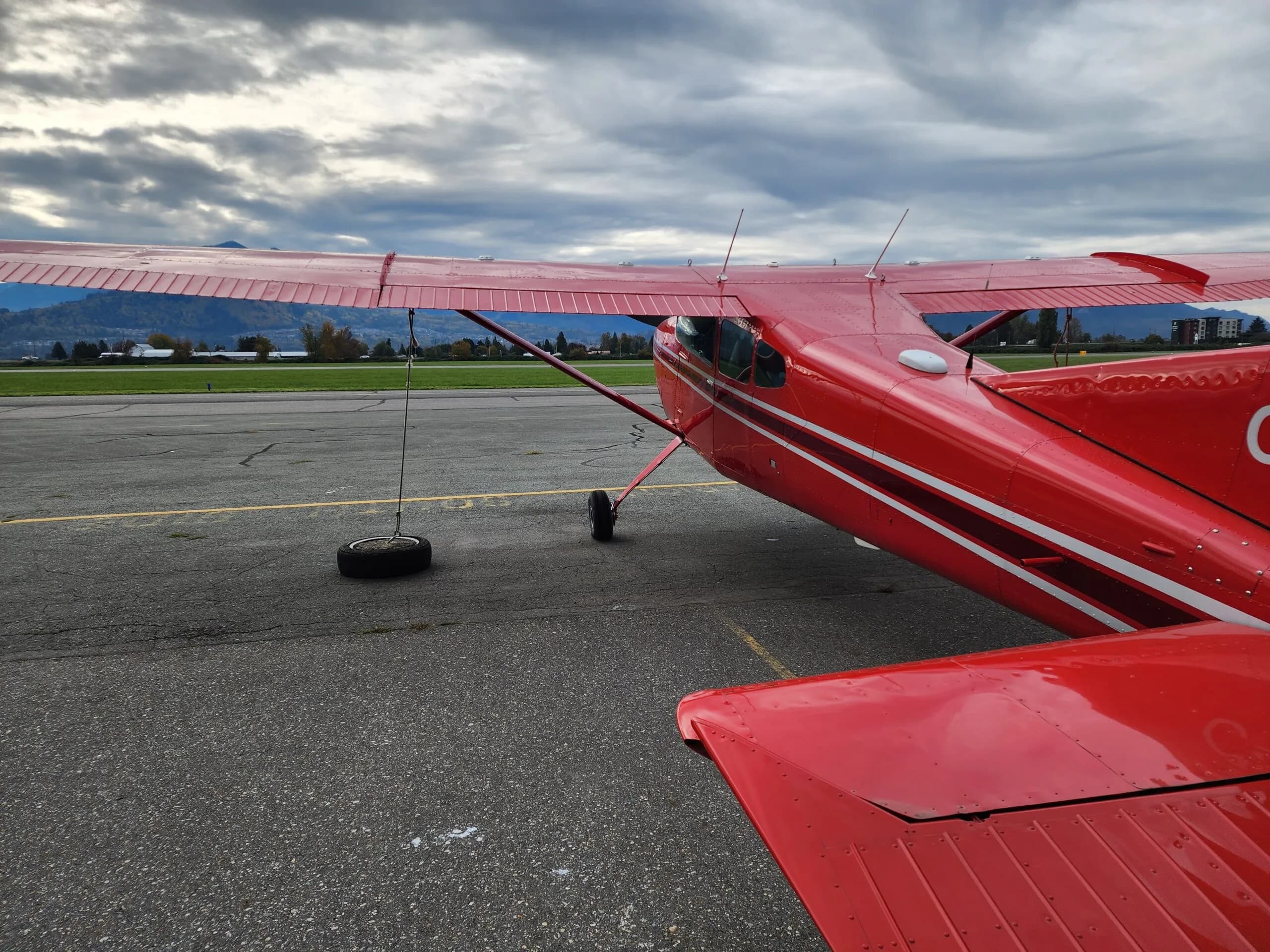 Close-up of the wing and fuselage of a red and white Cessna aircraft on the tarmac.
