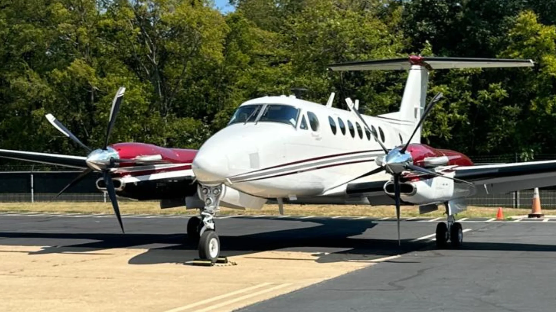 A white and red Beechcraft King Air N888FM seen from the front, parked on an asphalt tarmac.
