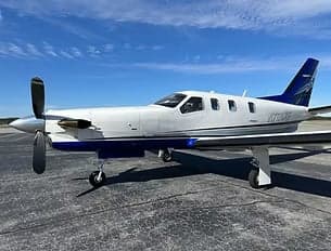 A white and blue TBM 900 aircraft is parked on the tarmac.
