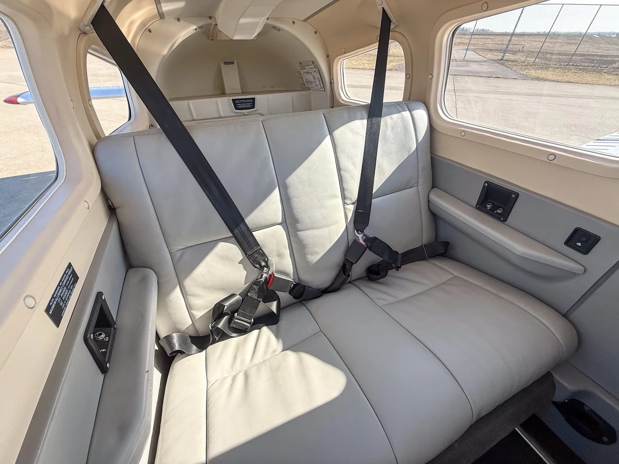 The light gray leather rear passenger seats of a Piper Archer TX cabin.