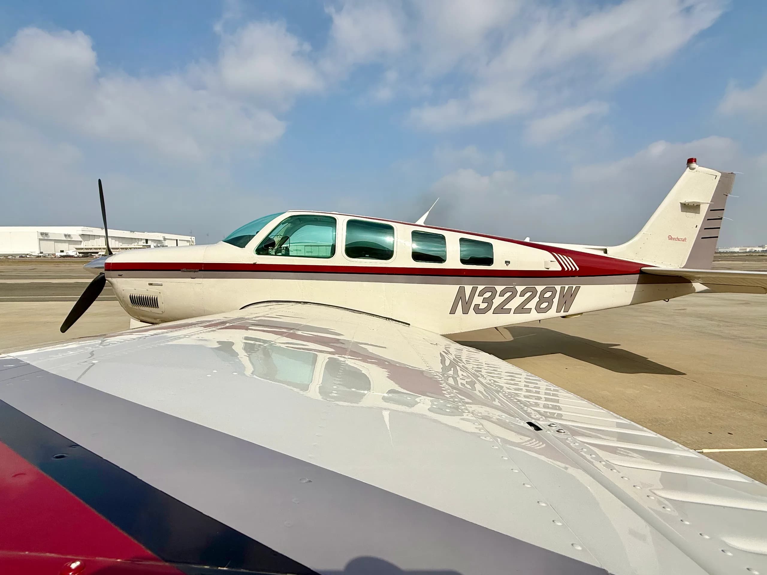 Side view of a Beechcraft Bonanza N3228W with a wing in the foreground.