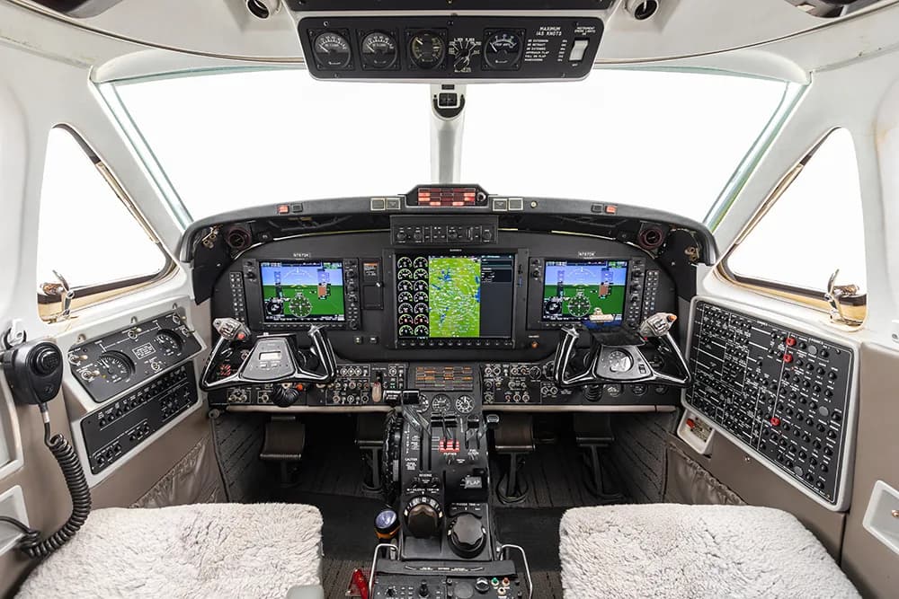 A detailed view of a modern aircraft cockpit with multiple digital displays and flight controls.