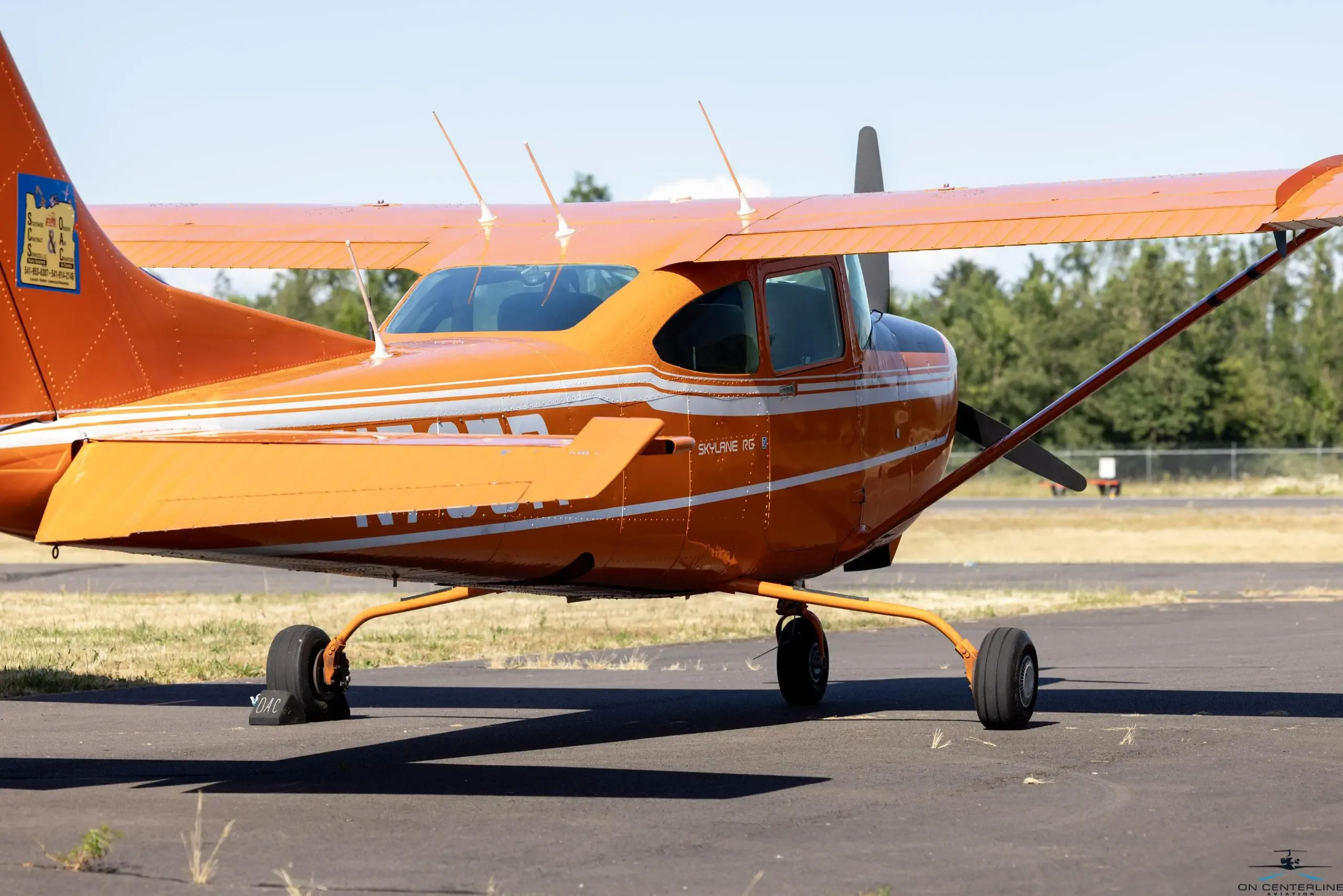 Rear quarter view of the orange and white Cessna 182 Skylane RG on the tarmac.