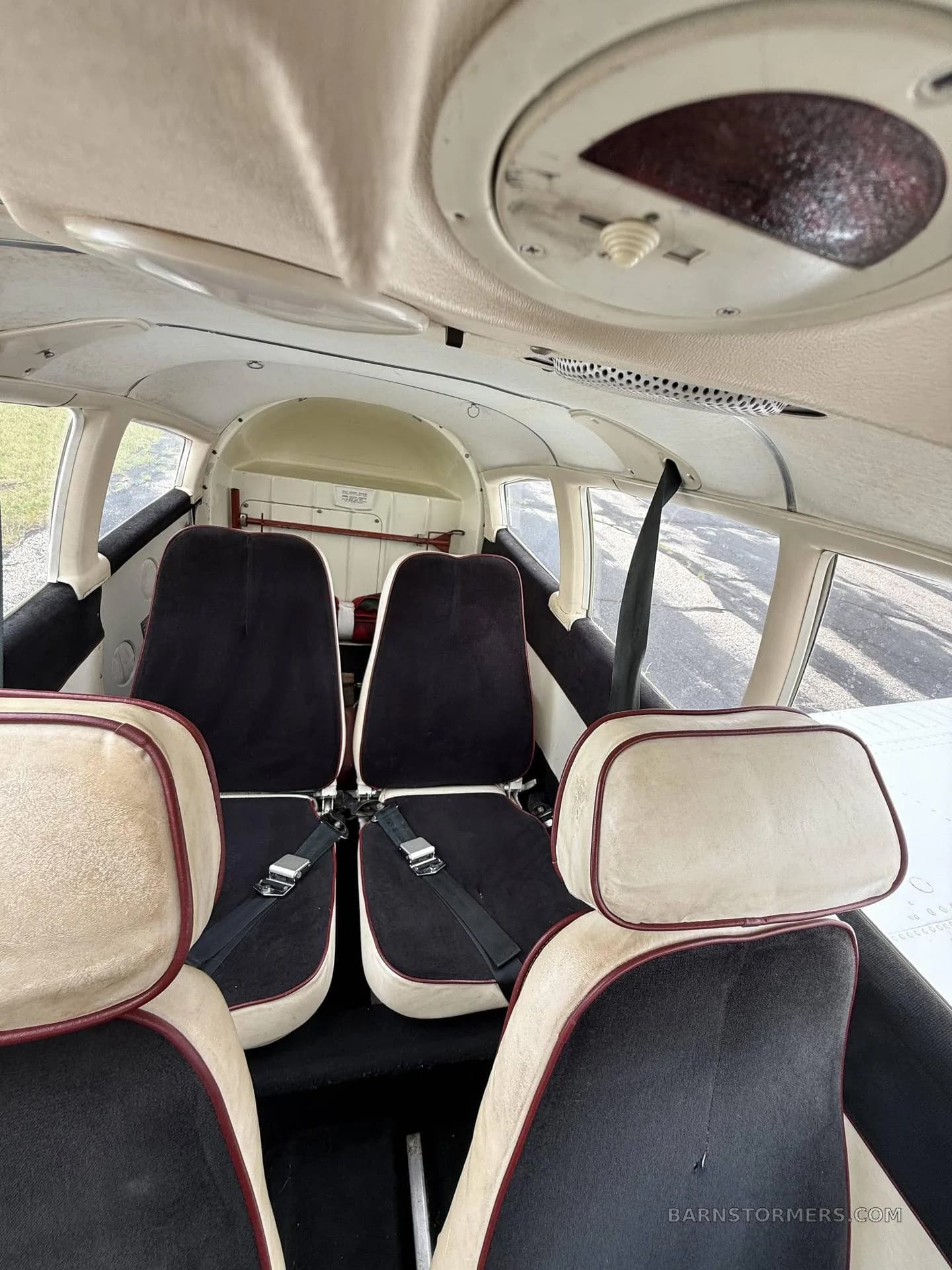 The interior cabin of a light aircraft showing two rear seats with black and beige upholstery.