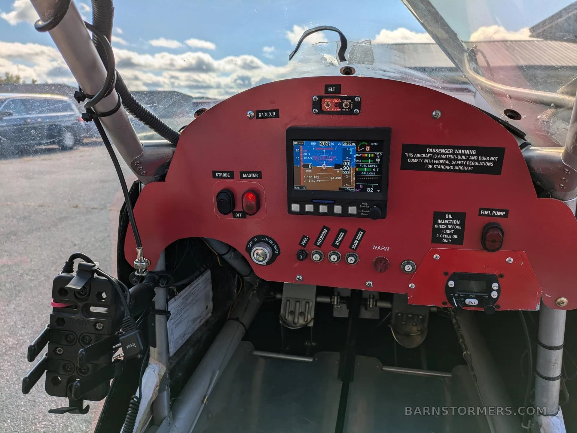 The red instrument panel of an ultralight aircraft, featuring a digital display, switches, and controls.