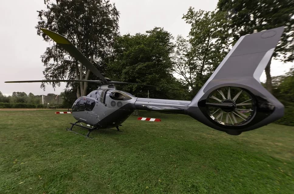 Rear view of a silver and black helicopter parked on the grass.