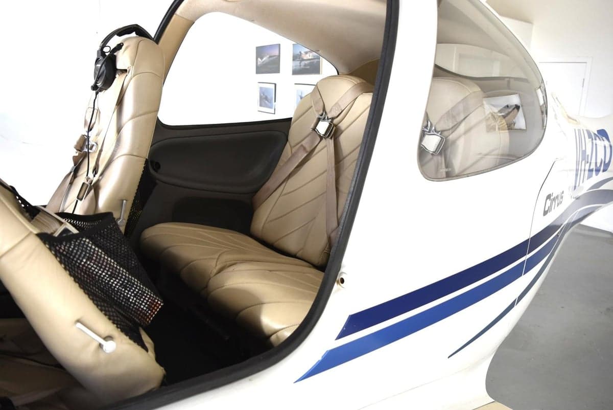 The beige leather interior of a Cirrus SR20 cabin, viewed from the open door.